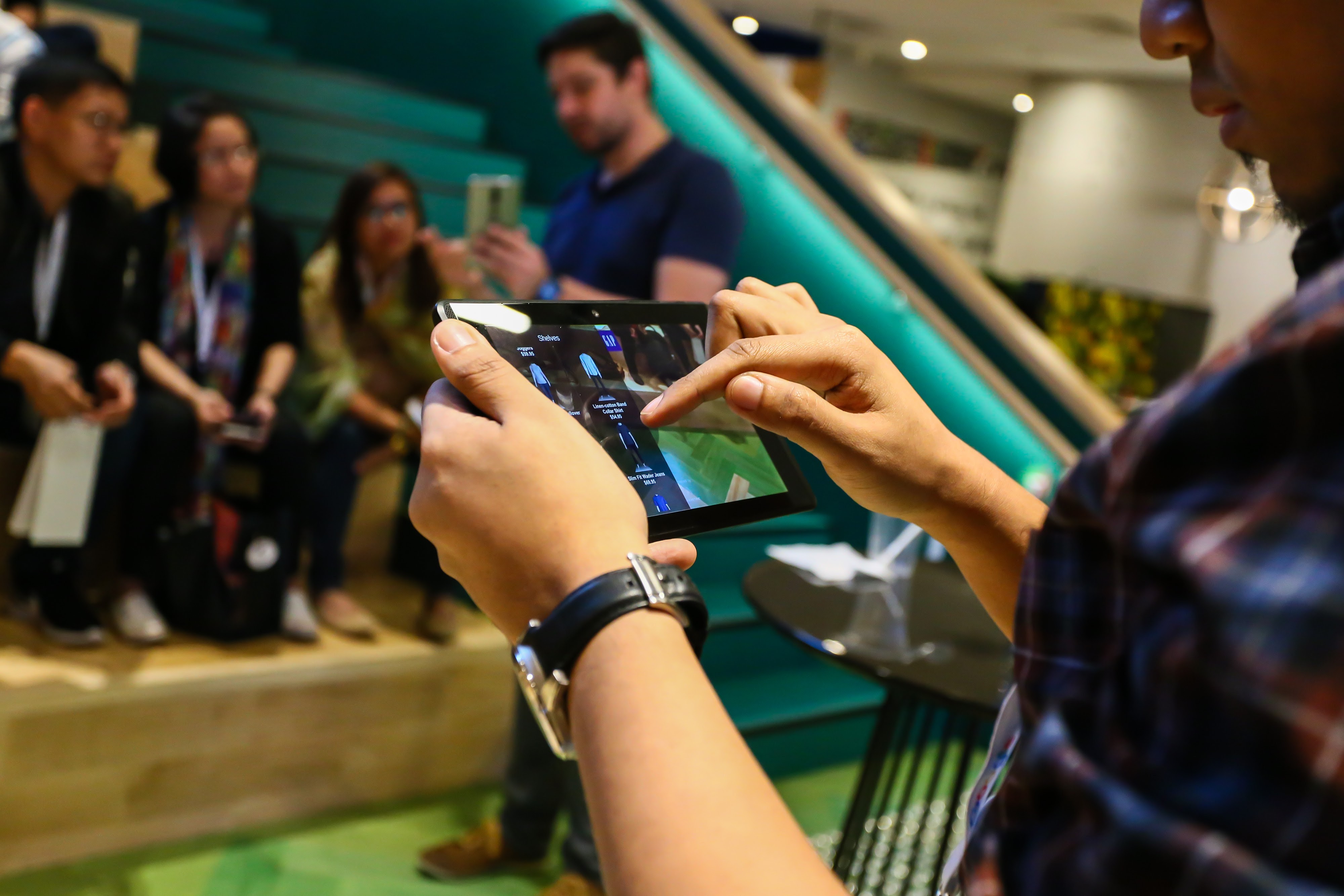 person looking at tablet, with group of people in the background